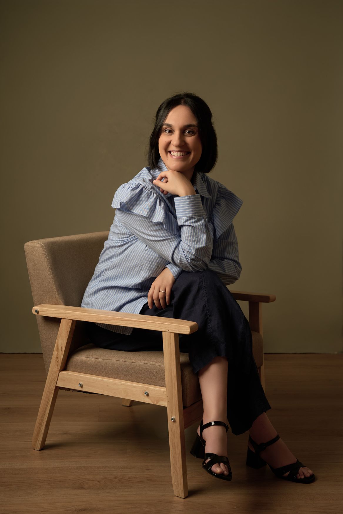 Giulia Milia sitting in a wooden armchair, smiling