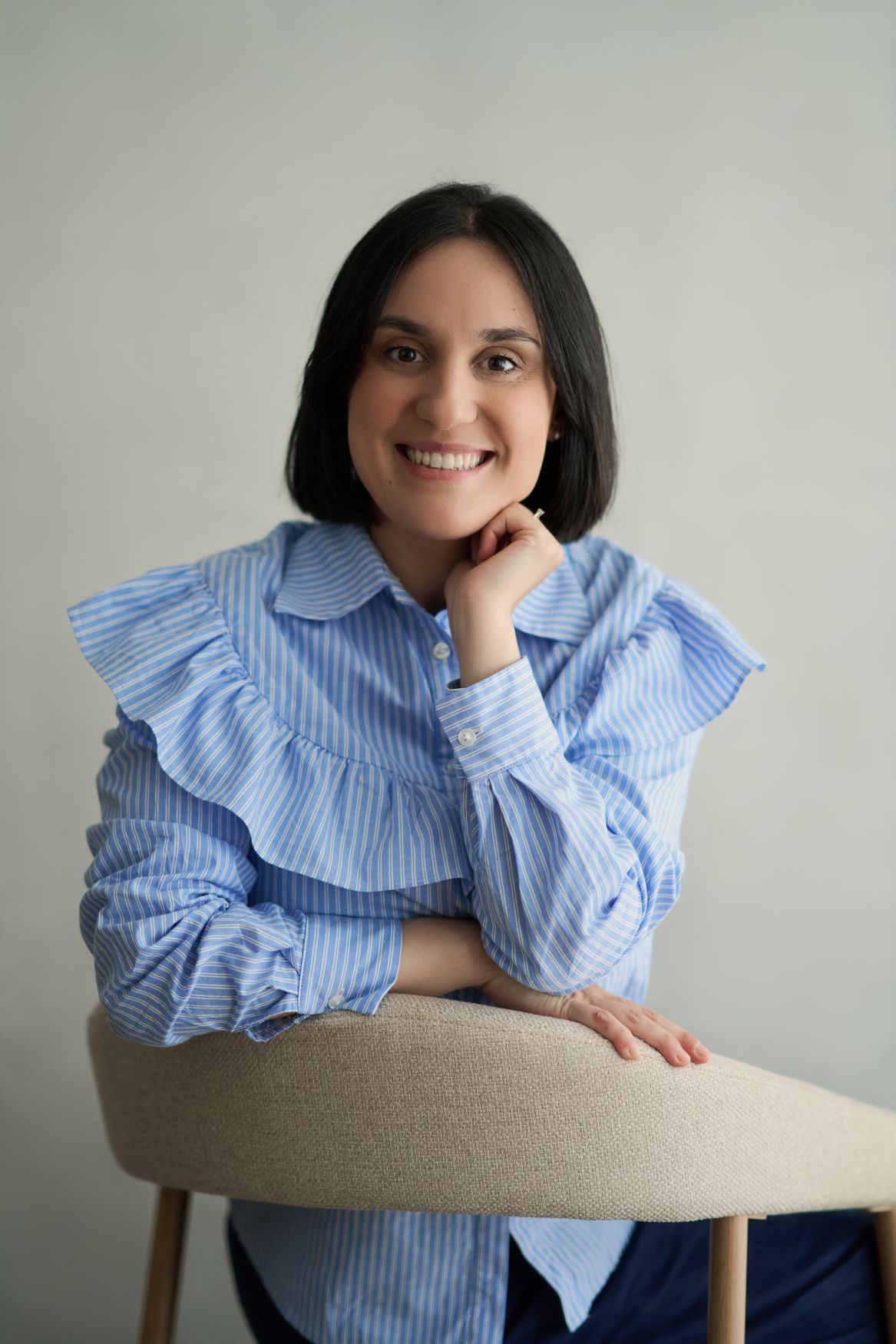 Giulia Milia smiling, leaning on the back of a chair