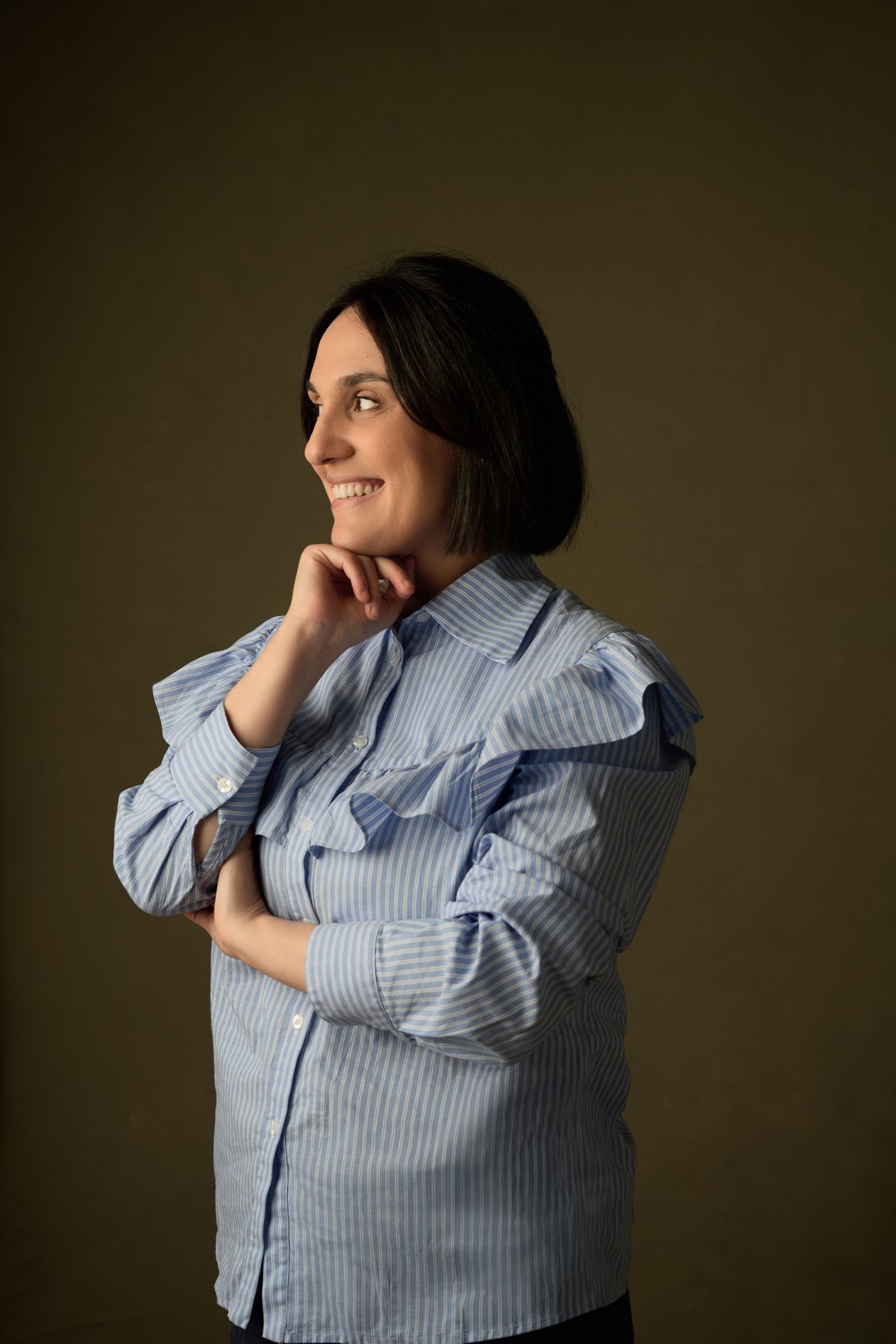 Giulia Milia in a striped shirt, smiling and looking to the side
